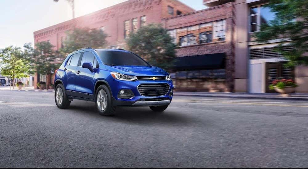 A blue 2017 Chevy Trax is shown driving on a city street.