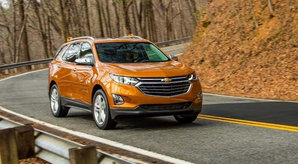 An orange 2018 Chevy Equinox is shown driving to a used dealership near Versailles.