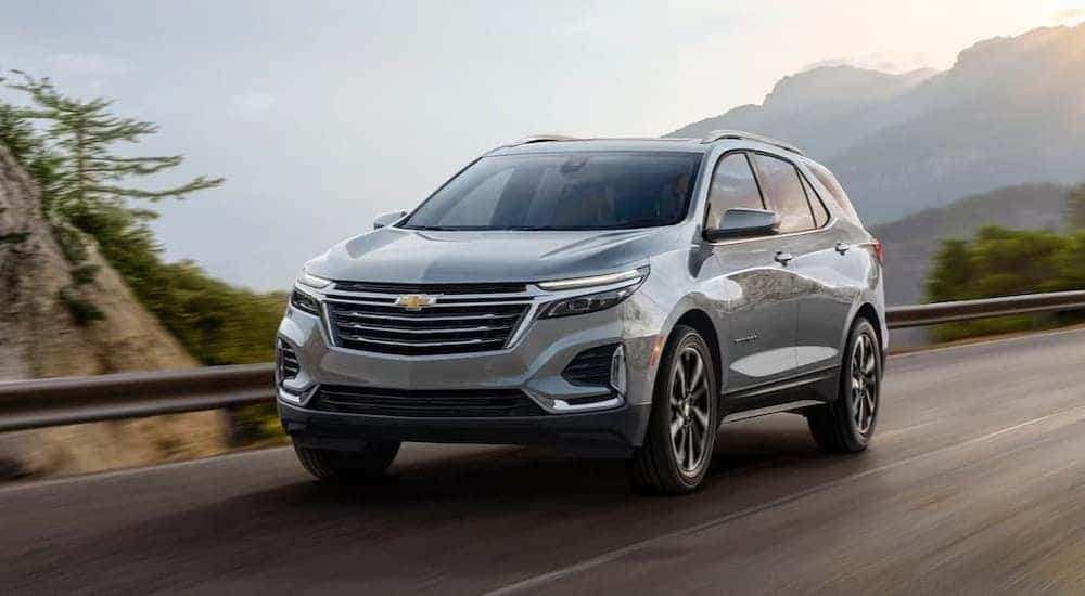 A silver 2024 Chevy Equinox Premium is shown driving to view a Chevy Equinox for sale.