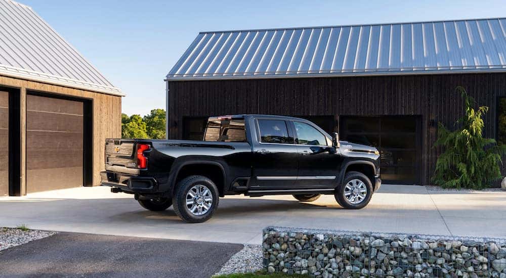 A black 2024 Chevy Silverado 2500 HD High Country is shown from the side after leaving a dealer that has a Chevy Silverado 2500 for sale near Charleston.