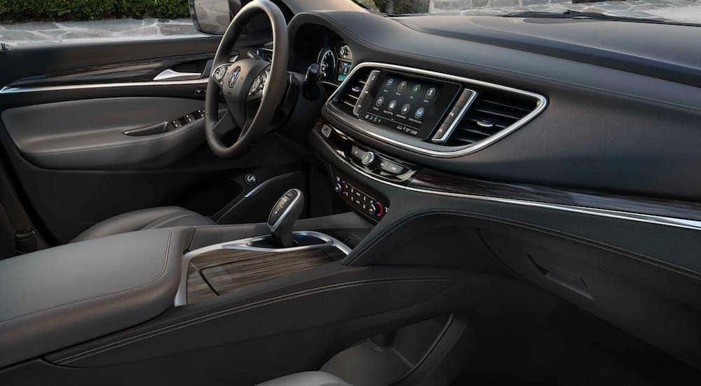 The black and gray interior and dashboard of a 2021 Buick Enclave is shown from the passenger seat.