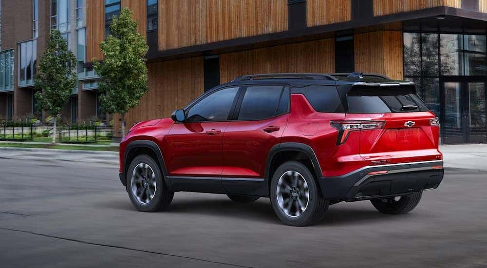 Rear view of a red 2025 Chevy Equinox RS driving through the city.