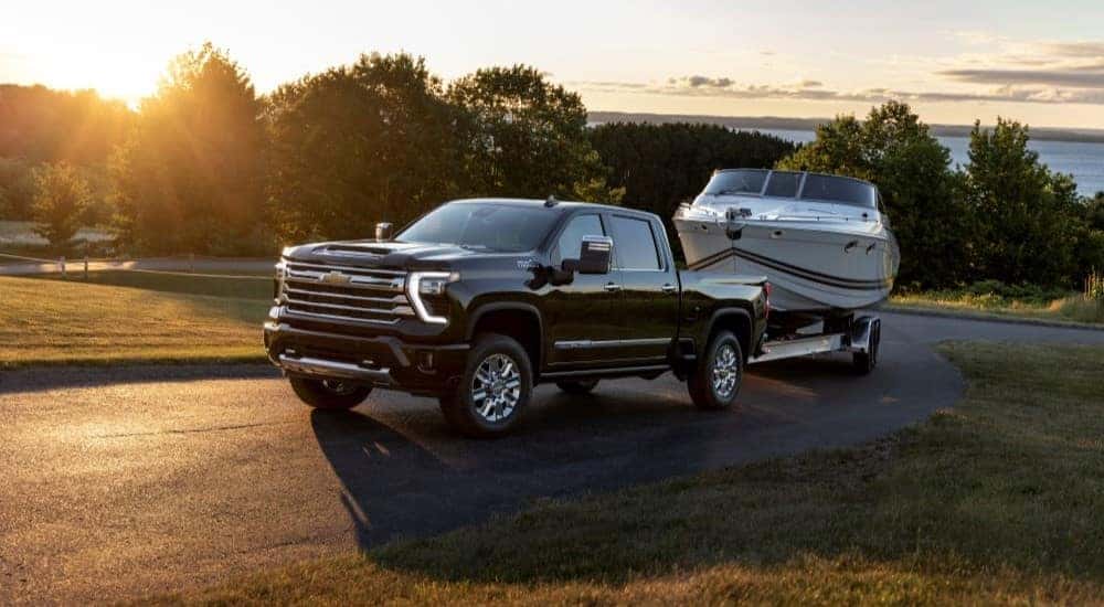A black 2024 Chevy Silverado 2500HD High Country towing a boat.
