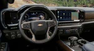 The black interior of a 2022 Chevy Silverado 1500 shows the steering wheel and infotainment screen.