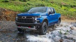 A blue 2022 Chevy Silverado 1500 ZR2 is shown off-roading through a river.