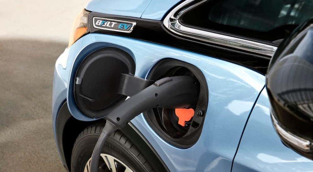 A closeup shows the charging port on a pale blue 2021 Chevy Bolt EV.