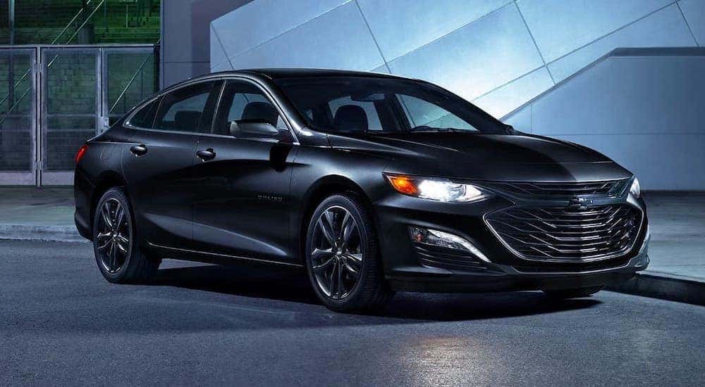 A black 2020 Chevy Malibu is parked in a modern gallery.