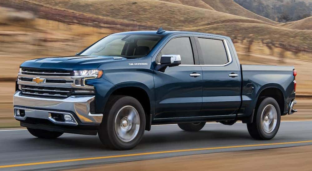 A blue 2021 Chevy Silverado 1500 is driving past a vineyard.