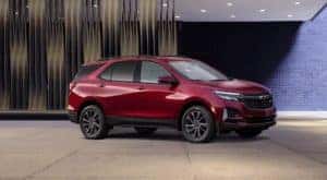 One of the most popular new cars in stock near you, a red 2022 Chevy Equinox RS, is shown in a modern lobby.