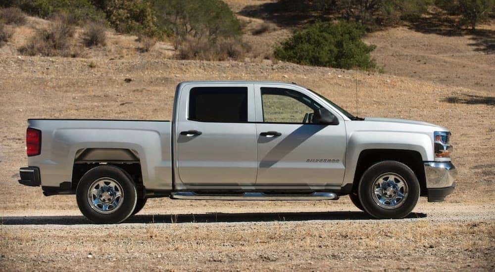 A silver 2018 Chevy Silverado 1500 is shown from the side parked on yellow grass after leaving a used auto dealer in Lexington, KY.
