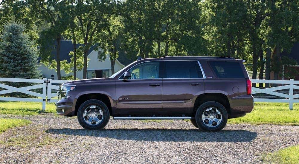 A burgundy 2017 Chevy Tahoe is shown from the side in front of a home near Lexington, KY.