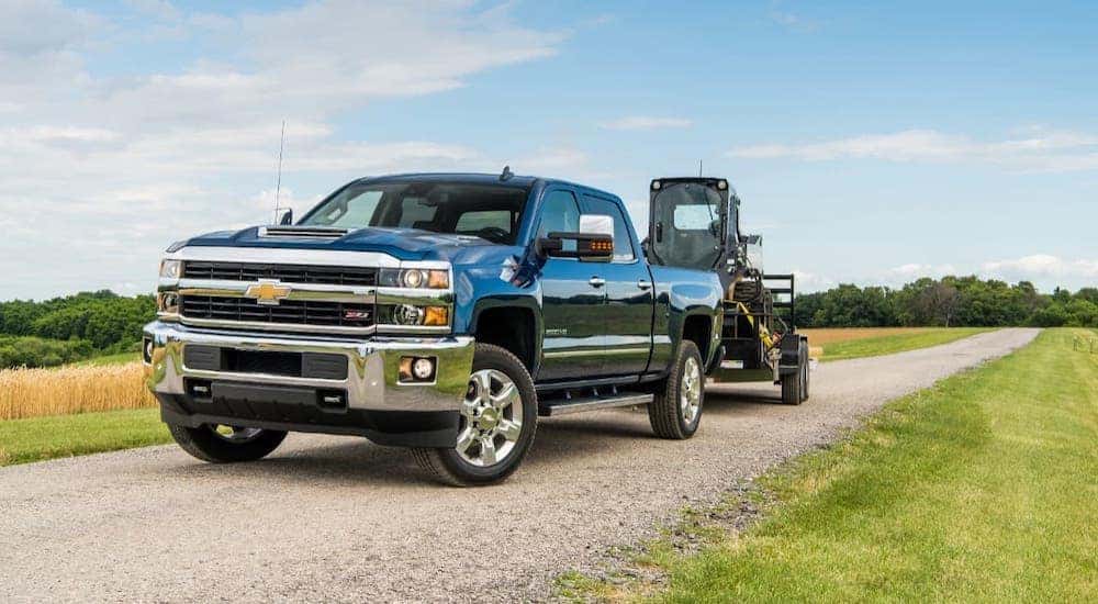 A black 2018 Chevy Silverado 2500HD is towing equipment on a highway near Lexington, KY, after leaving a used car dealer near you.