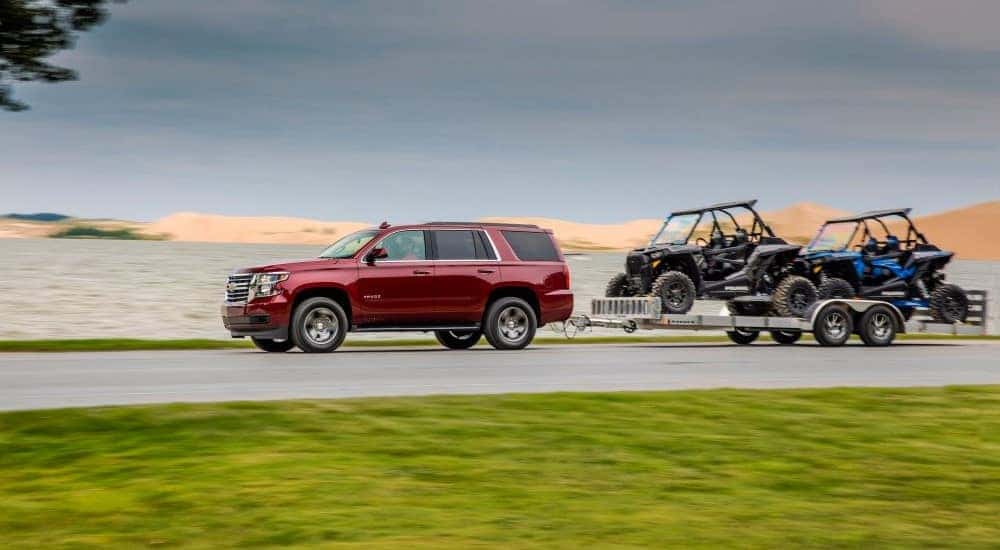 A red 2018 Checy Tahoe is shown towing ATvs.