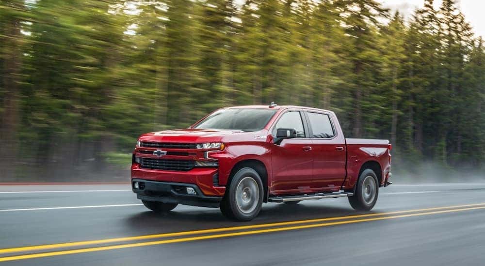 A red 2020 Chevy Silverado 1500 Z71, a popular used Chevy Silverado 1500 for sale, is shown driving on an open road.