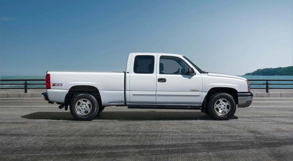 A white 2006 used Chevy Silverado is shown in profile with a lake in the background.