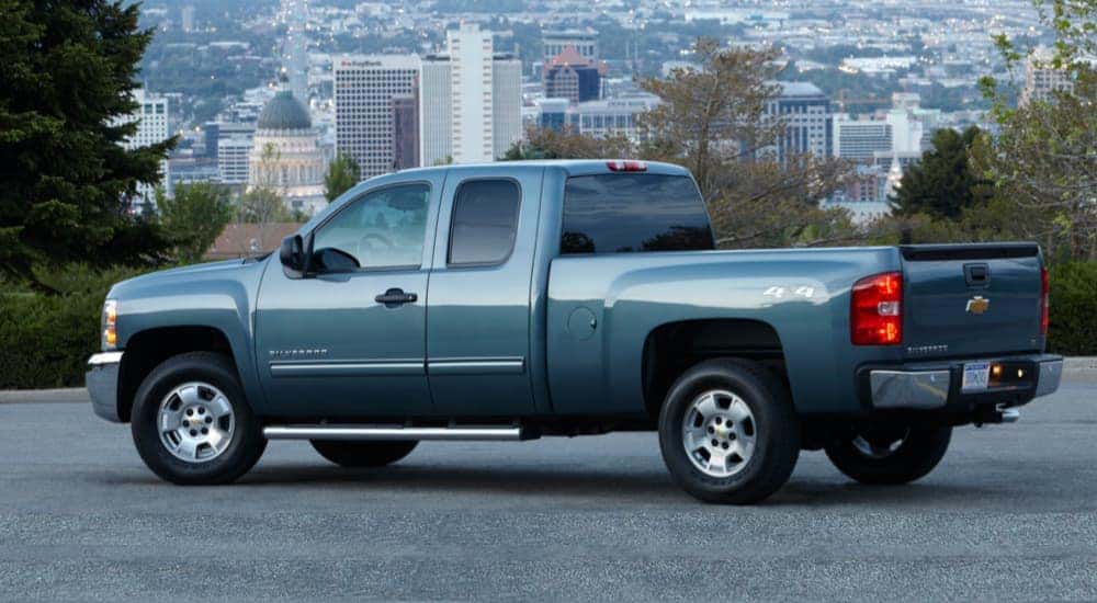 A blue 2013 used Chevy Silverado LT is parked with a city in the background.