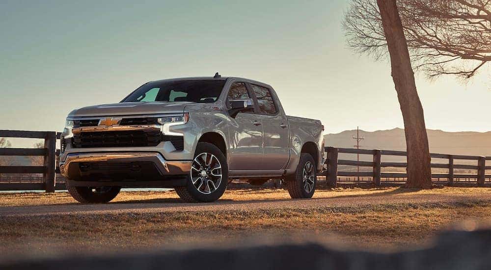 A silver 2022 used Chevy Silverado for sale is shown near a fence.