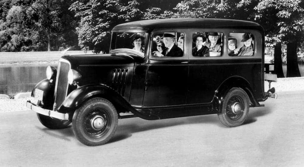 A black 1935 Chevy Suburban full of people is shown in black and white.