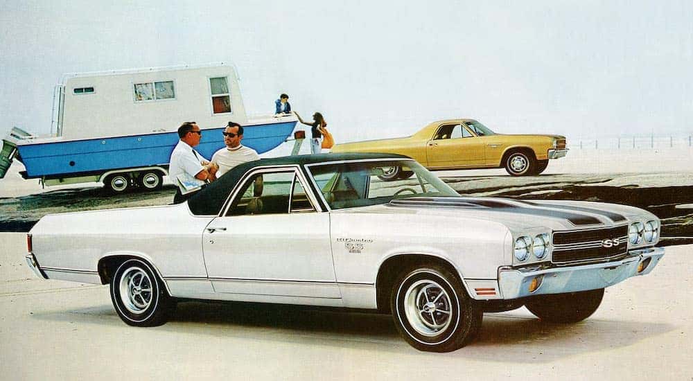 A white 1970 Chevy El Camino SS is shown with a yellow El Camino towing a boat in the background.