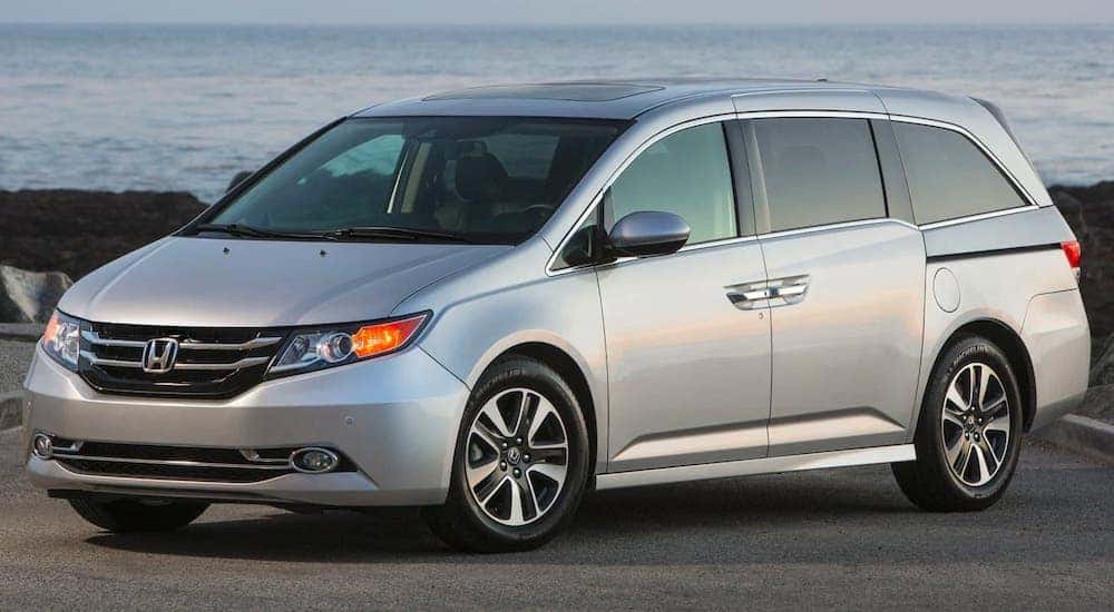 A silver 2015 Honda Odyssey is parked in front of a beach.