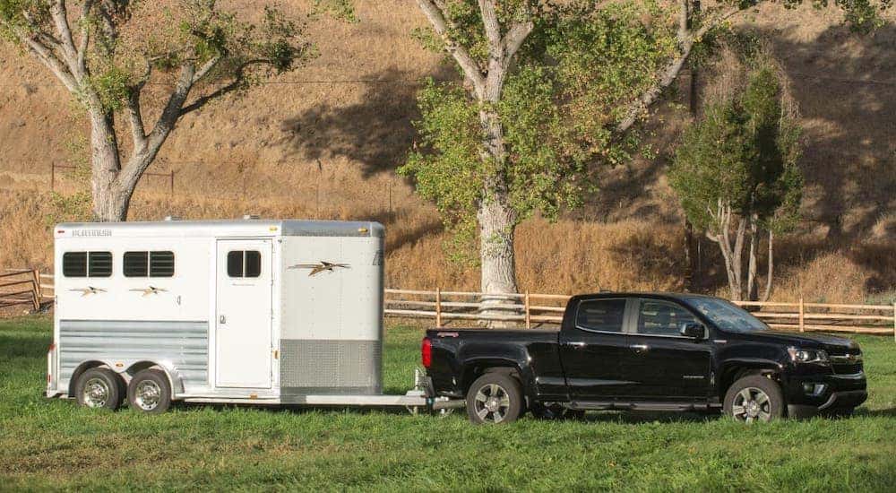 A black 2017 Chevy Colorado is towing an enclosed horse trailer.