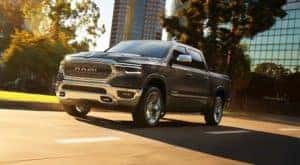 A grey 2019 Ram 1500 is shown from a low angle driving in a city.