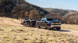 A black 2020 Chevy Silverado 1500 is shown towing two ATVs.