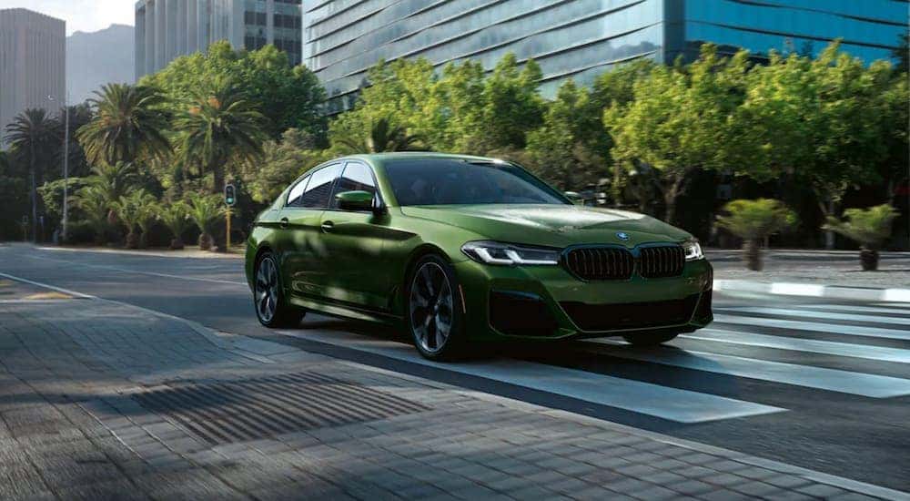 A Green 2021 BMW M550 i XDrive is driving through a city.