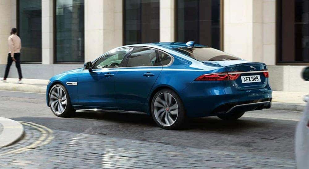 A blue 2021 Jaguar FX is taking a turn through a city.