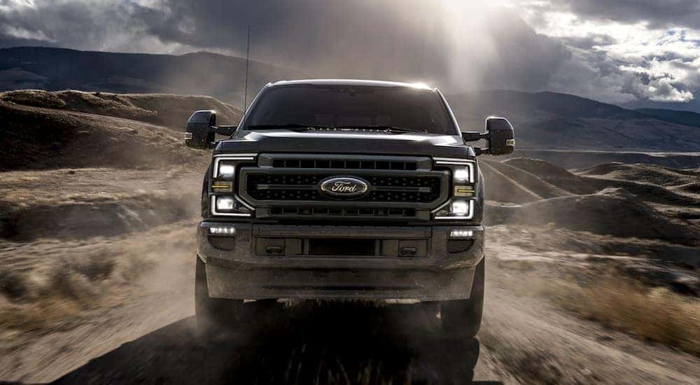 A black 2020 Ford F-250 SD is shown from the front is driving down a dirt road.