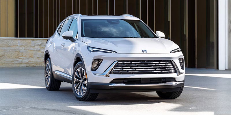 White Buick Envision parked on the steert in the shade when it is sunny outside