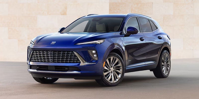 Blue Buick Envision parked on a street next to a big beige building