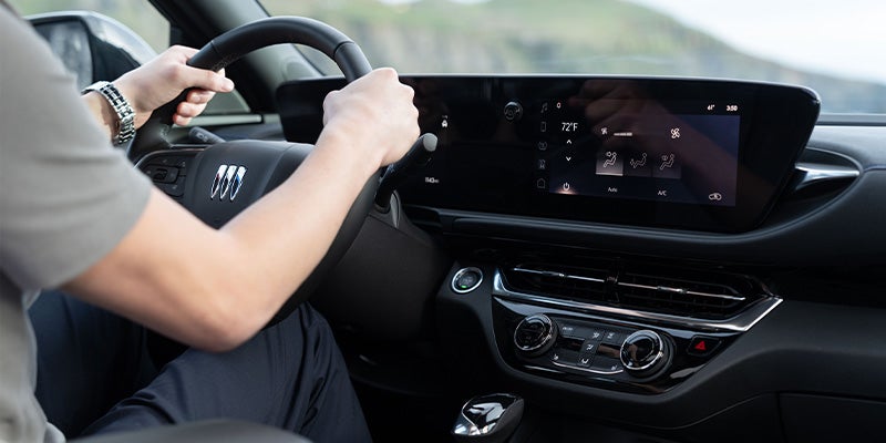 Interior design of a Buick Envista while someone is holding the steering wheel