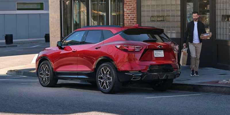 Red Chevrolet Blazer parked on the street during the day as two people walk by the vehicle