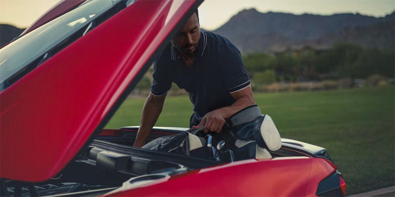 Chevrolet Corvette Stingray parked on the street as a man opens up the trunk to collect his items