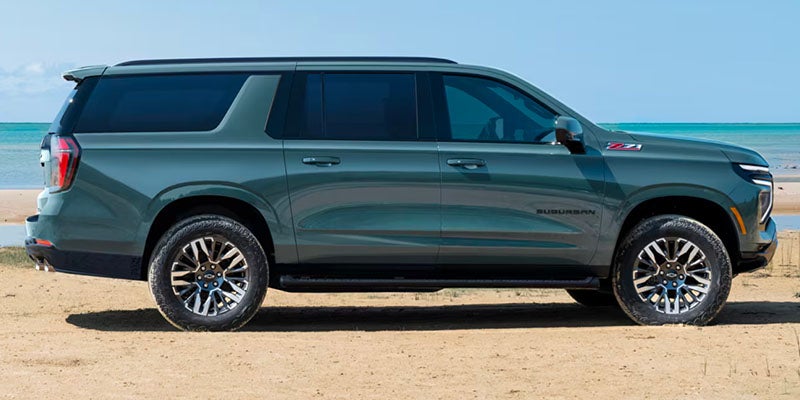 Gray Chevrolet Suburban parked on the beach during a sunny day outside