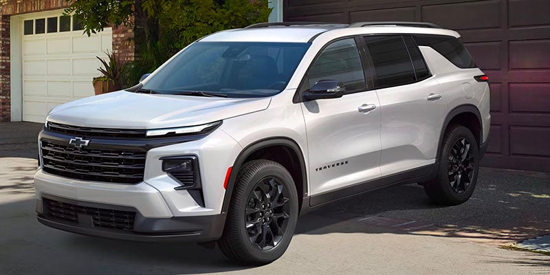 Traverse parked on the driveway next to a big house