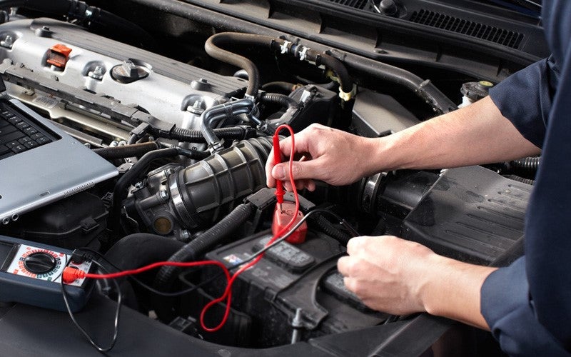 Mechanic at Dan Cummins Chevrolet Buick Paris dealership recharging a small battery